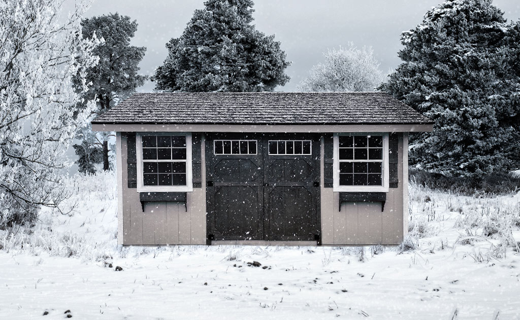 Gray garden shed with black double doors and trim on a snowy day