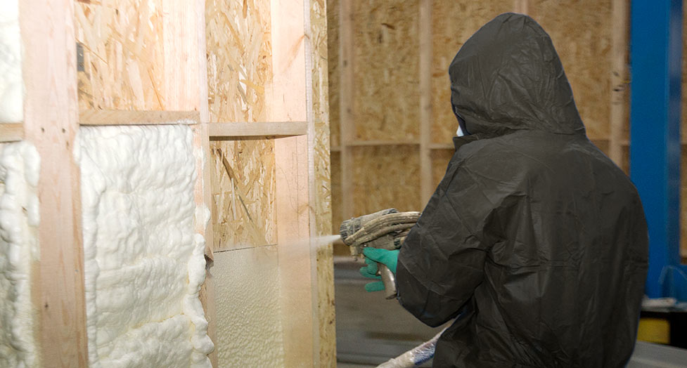 Person spraying insulation in walls of building