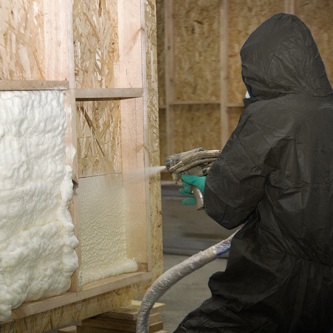 Person spraying insulation into walls of building
