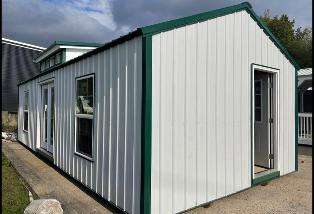 White vertical a frame style portable building with green trim