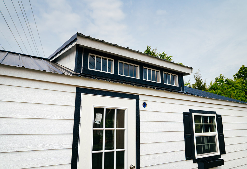 White portable building with black trim and dormer window